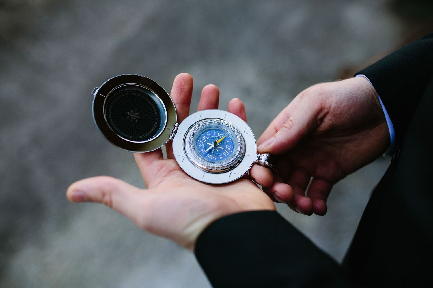 A person in a suit holds an open compass in their palm, symbolizing direction, navigation, and guidance.