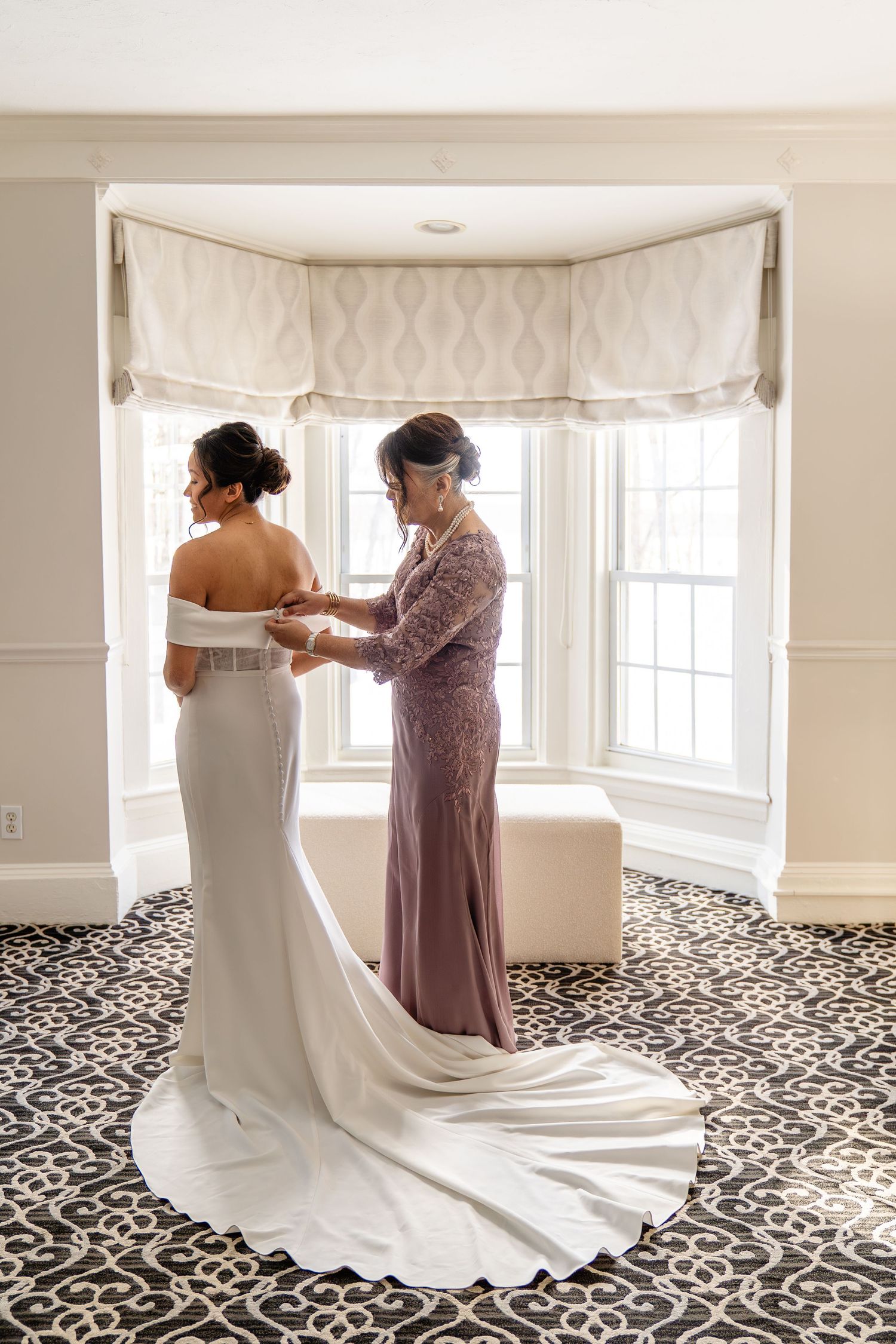 Bride getting help into wedding gown by mother at The Saphire Estate