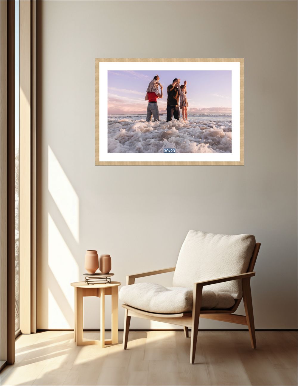 Framed photo print of people standing in ocean waves at sunset, displayed on a beige living room wall above a chair.