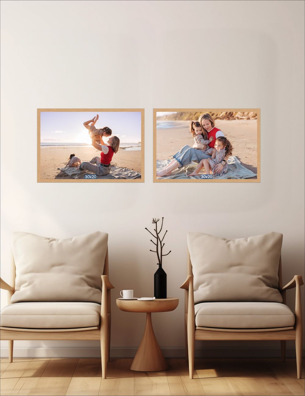 Two framed beach family photos displayed on a white wall above two beige armchairs with a small side table.