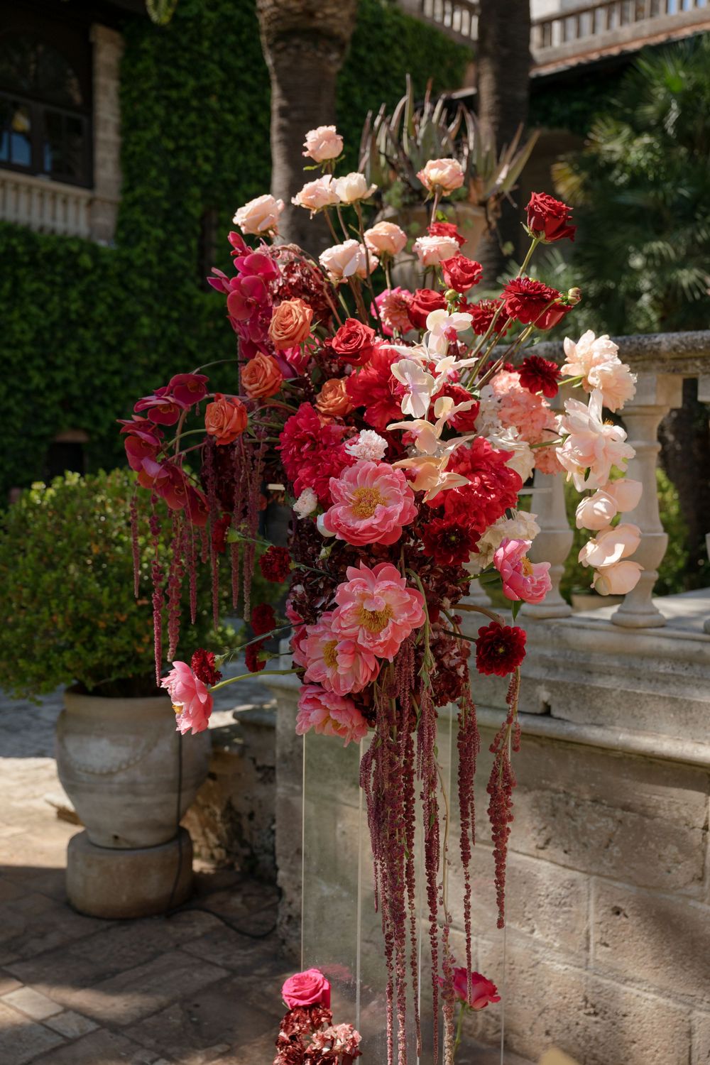 Elegant floral arrangement with pink, red, and blush roses cascading outdoors at a luxury venue.