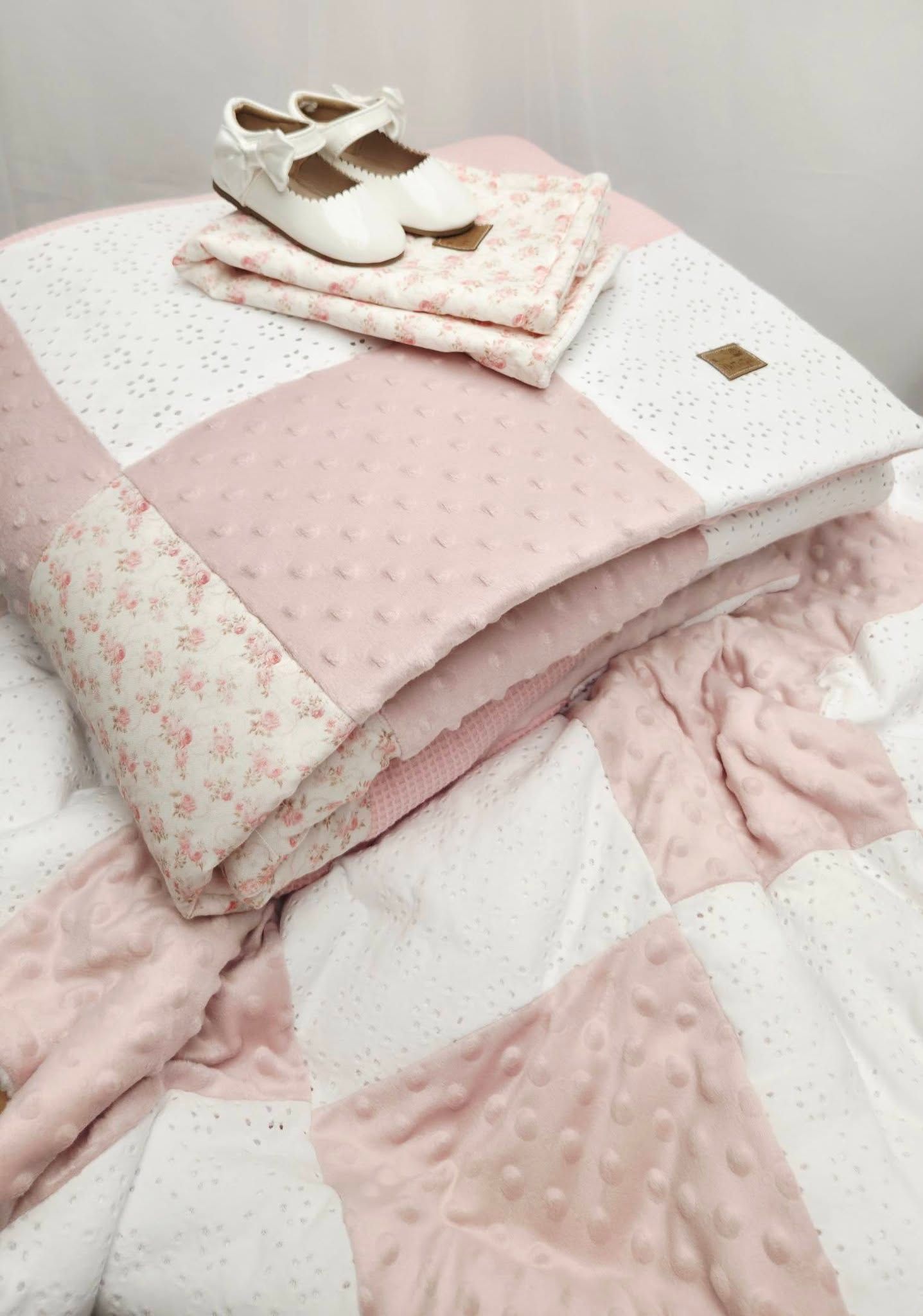 Pink and white patchwork baby quilt with minky fabric, paired with white Mary Jane shoes and floral print cloth.