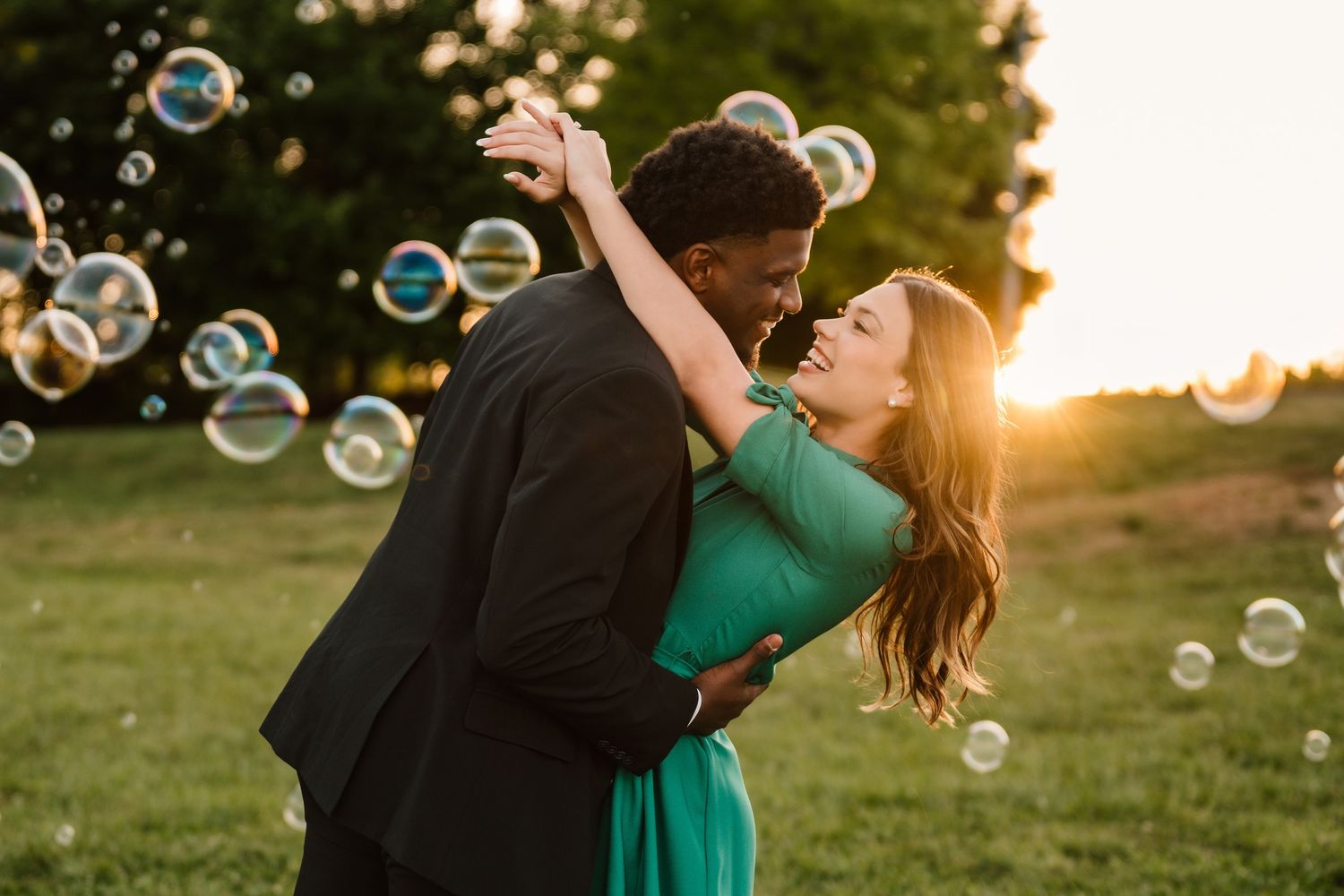 Couple dancing at NC Museum of Art NCMA surrounded by floating bubbles in a lush green park, woman in green dress.