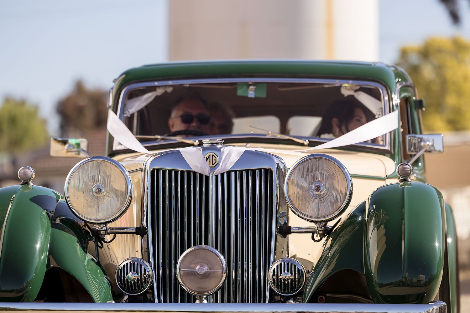 A vintage green car with distinctive round headlights and chrome grille at the Corowa Distilling Co. bringing the Bridal party to a wedding.