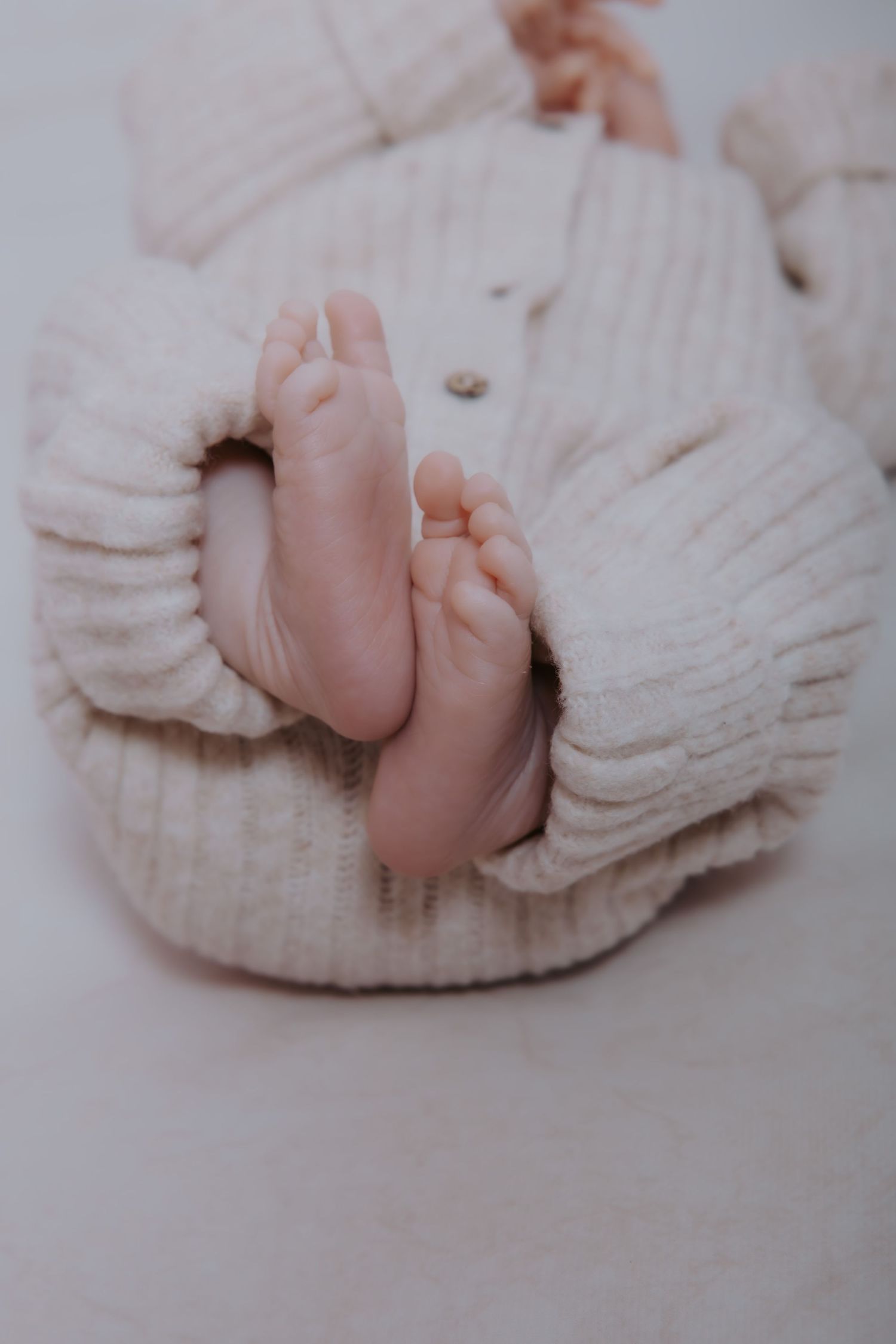 Series of delicate baby feet photos wrapped in soft white knit fabric.