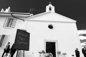 Panoramic view of a white church exterior with cross on top against dark sky.