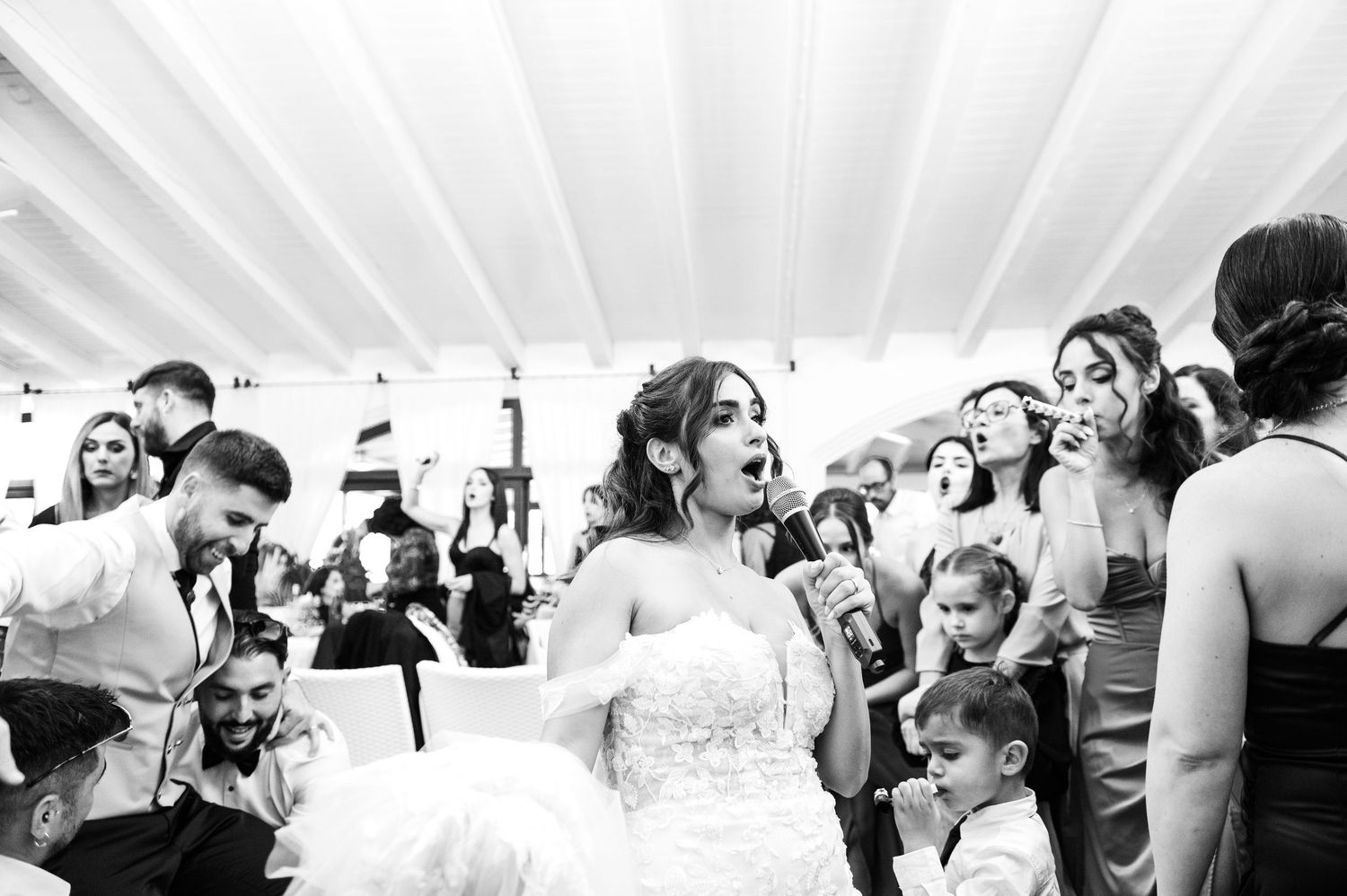 Joyful wedding celebration with guests dancing and laughing under a white tent.