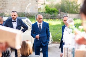 Groomsmen in navy suits walking and chatting outdoors.