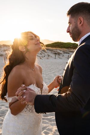 Romantic couple sharing intimate moments on a sandy beach at sunset.