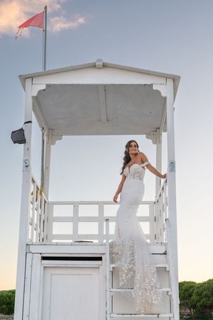 White wedding dress photographed at a beachside lifeguard tower.