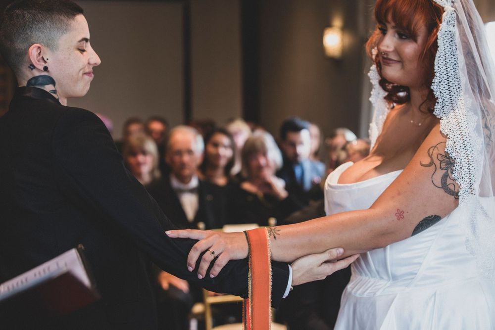 Wedding ceremony in progress with guests seated in elegant indoor venue.