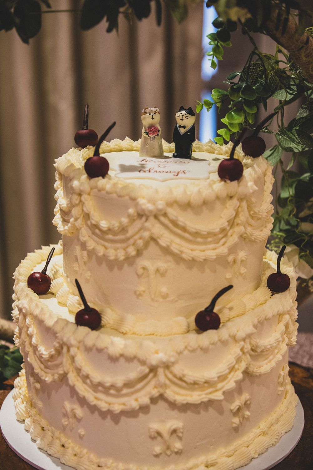 Elegant white wedding cake decorated with intricate piping details and fresh cherries on top.