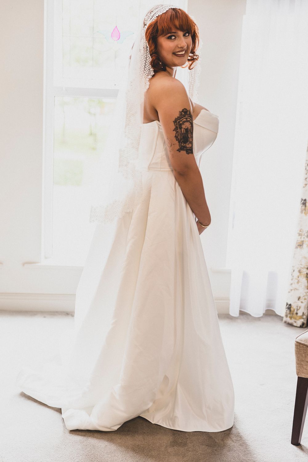 A bride in a flowing white wedding dress twirls gracefully in a bright sunlit room.