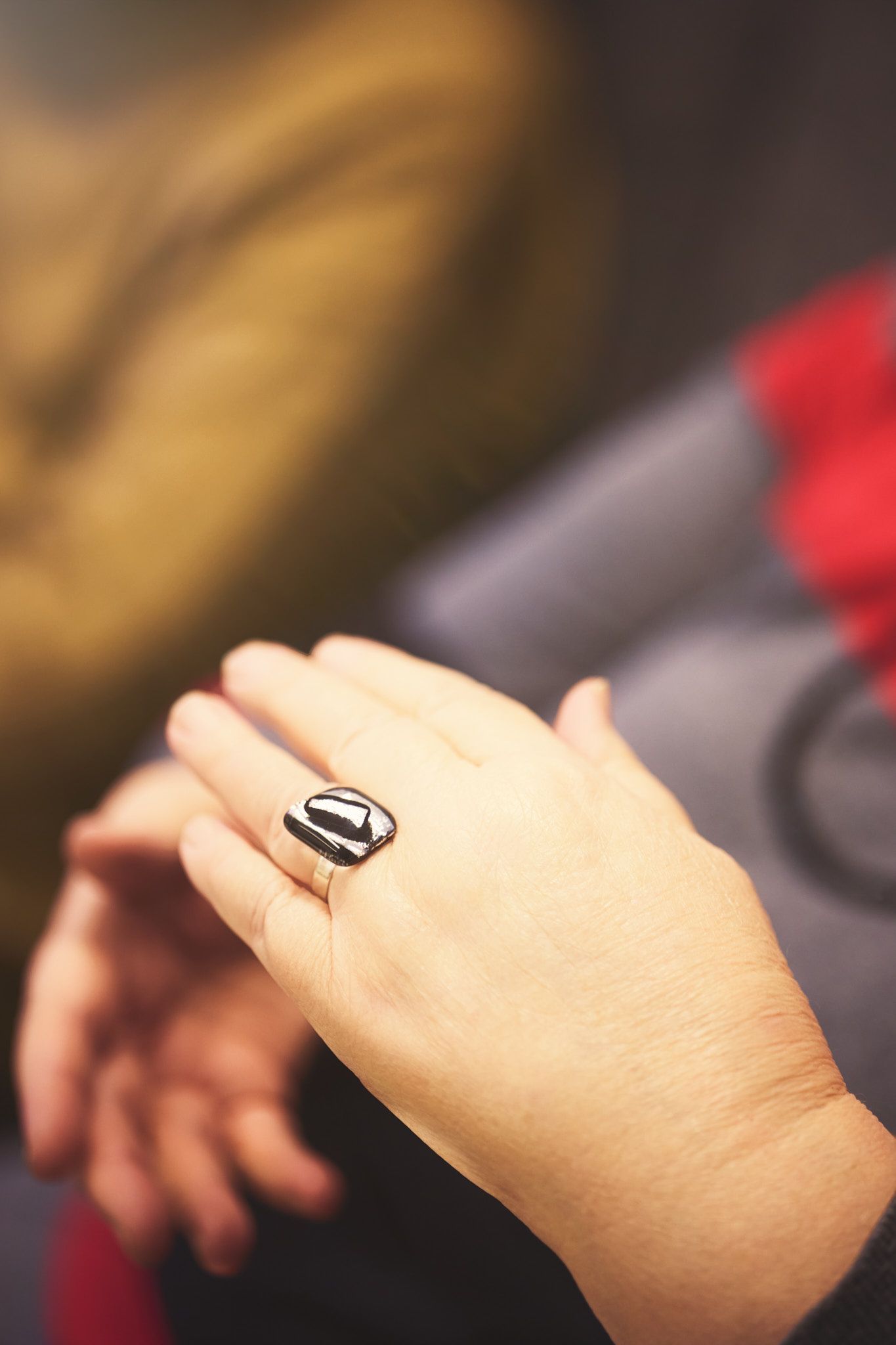 Hands wearing rings shown in detail against a blurred background.