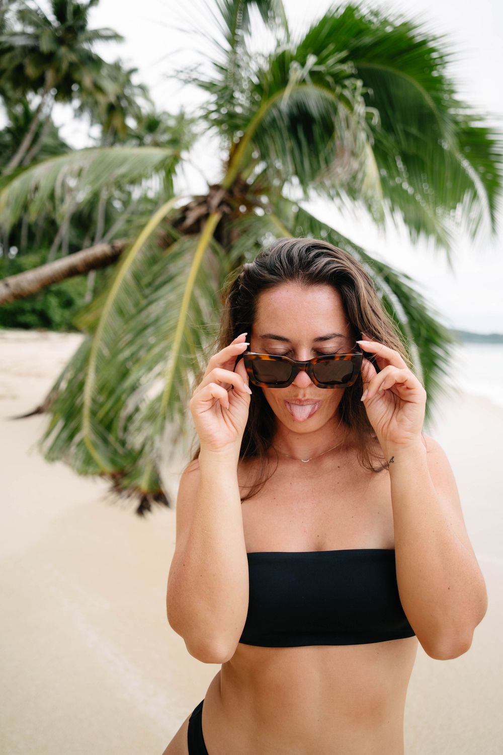 A sequence of photos showing someone in a black swimsuit adjusting sunglasses with palm trees in the background.