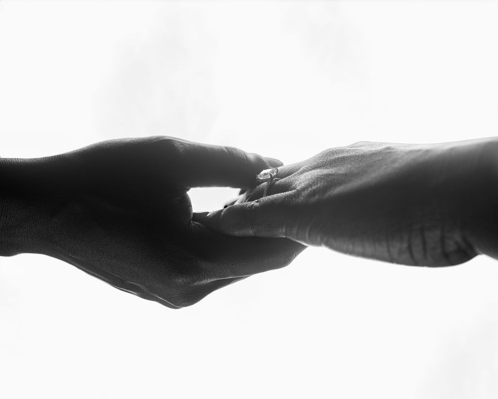 Two hands reach out to each other in silhouette against a white background, symbolizing connection and unity.