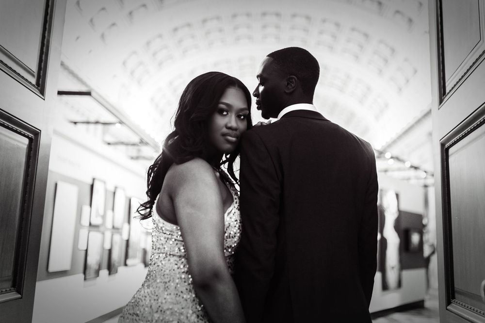 Black and white wedding photography shows couple in romantic silhouette along hallway with elegant lighting.