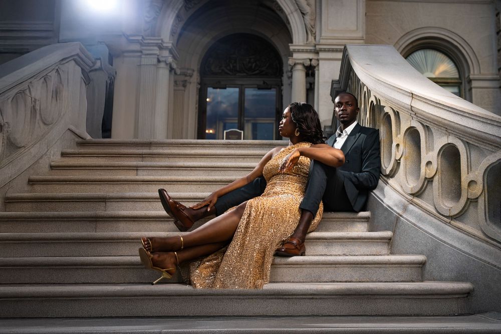 A person in an elegant gold dress lies gracefully across marble stairs in an ornate architectural setting.