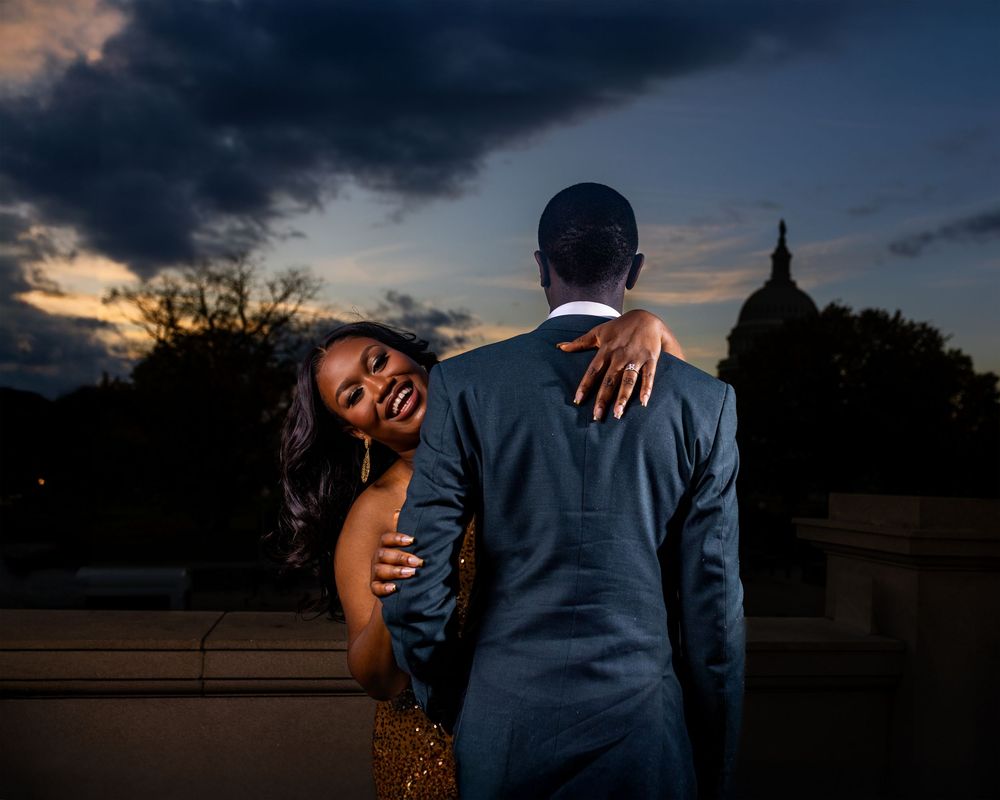 A couple embraces during a romantic sunset photoshoot in a dramatic outdoor setting.
