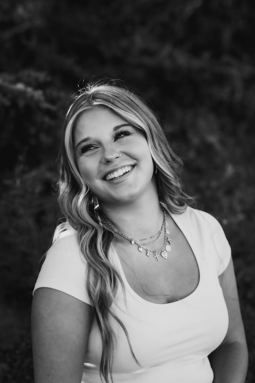 Black and white portrait of someone laughing joyfully against a dark background.