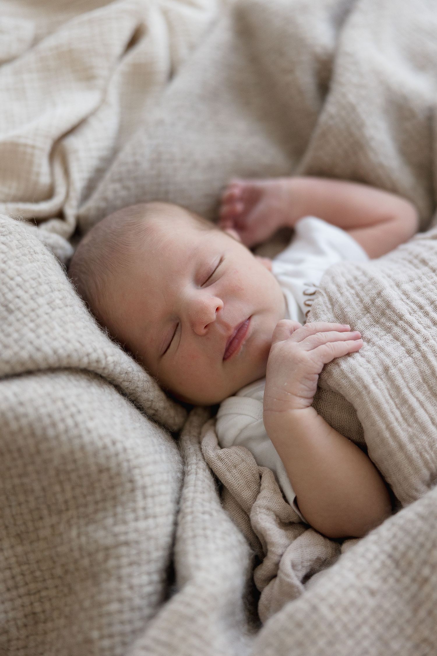 A series of tender moments between mother and newborn baby in soft beige tones against a neutral grey backdrop.