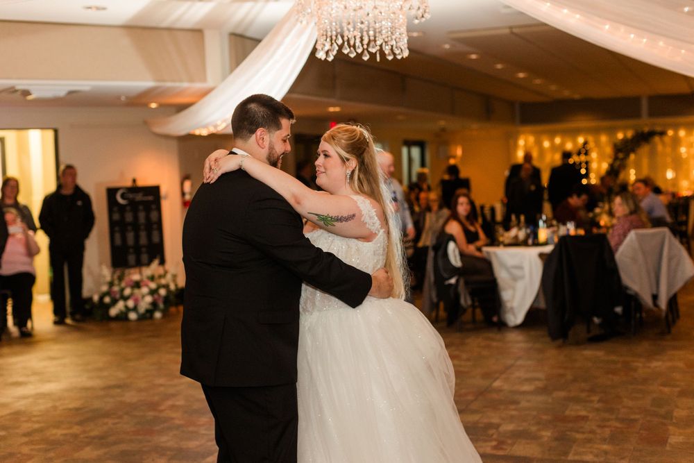 Couples dancing at an elegant wedding reception under crystal chandeliers in a warmly lit ballroom.