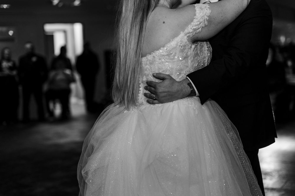 A bride and groom share an intimate dance moment at their wedding reception in black and white photography.