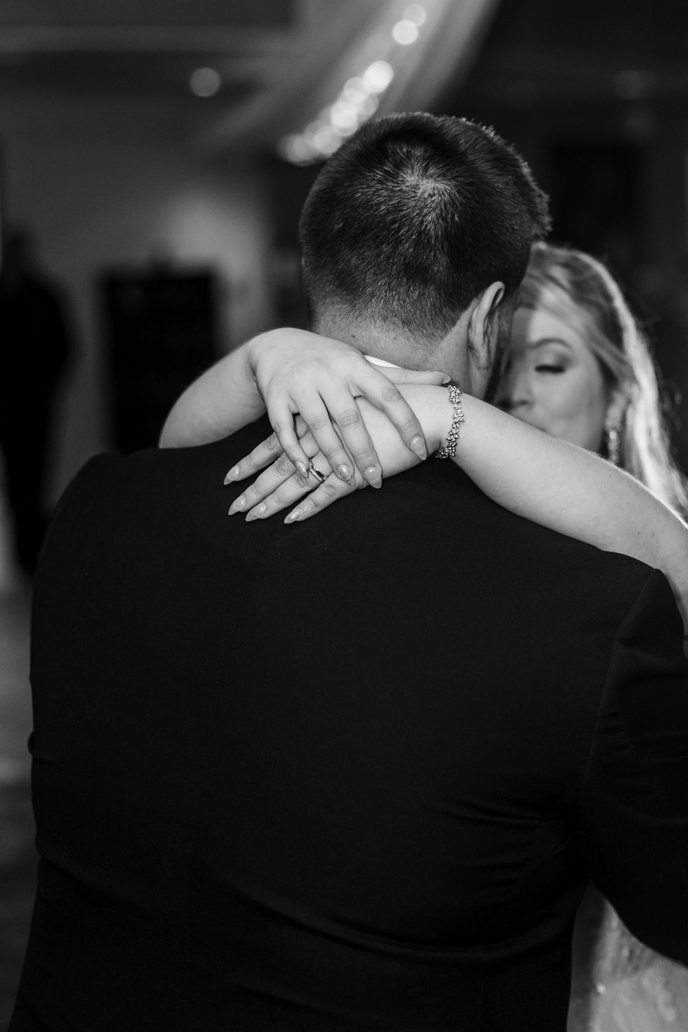 A couple shares an intimate dance at a wedding reception in black and white photography.
