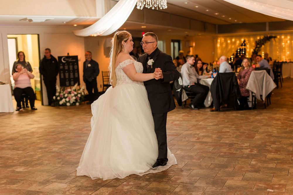 A wedding reception dance floor scene with couples dancing in an elegant ballroom with warm lighting.