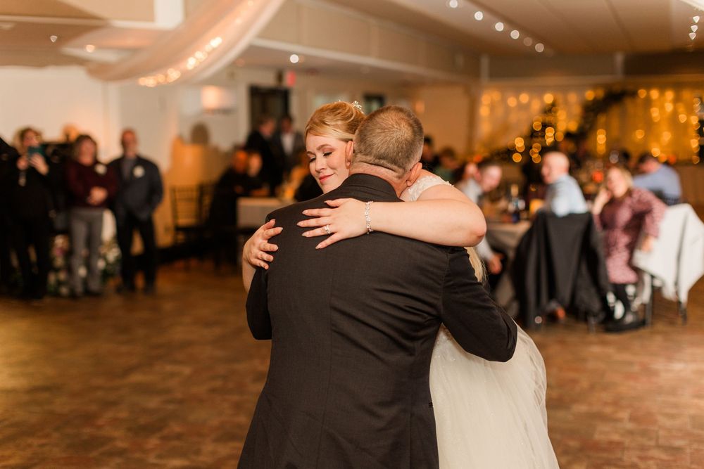 Wedding guests dancing together in a beautifully decorated ballroom with warm ambient lighting.