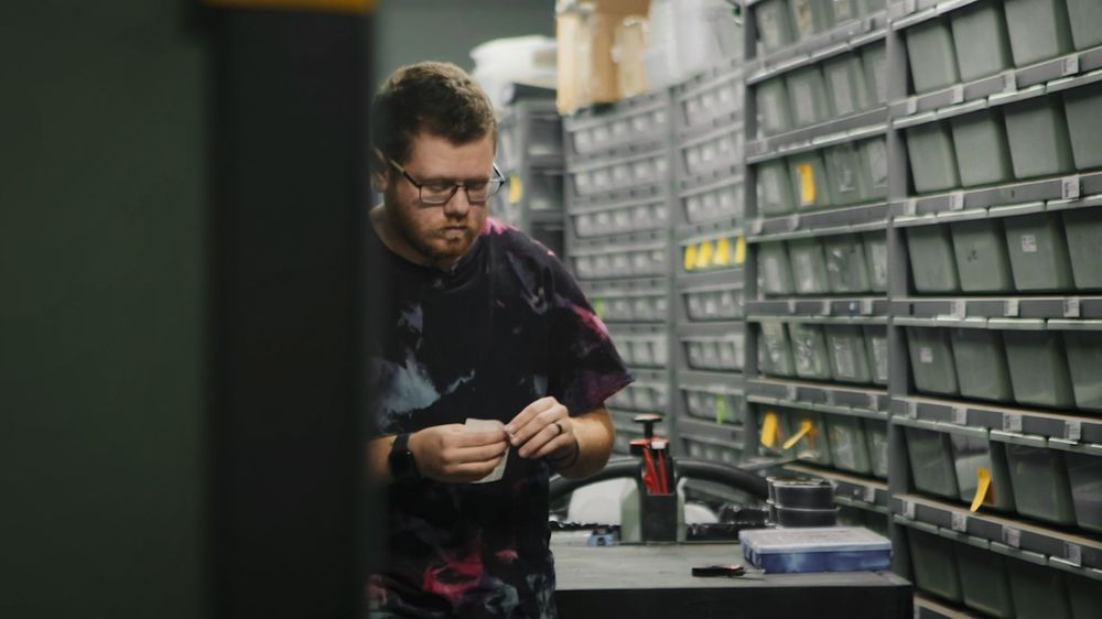 A pharmacist browses through shelves of organized medications in a pharmacy storage area.