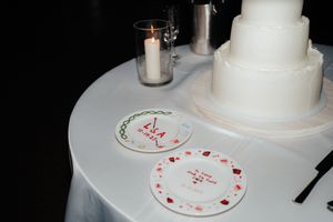 White wedding cake with delicate red heart decorations displayed on a table.