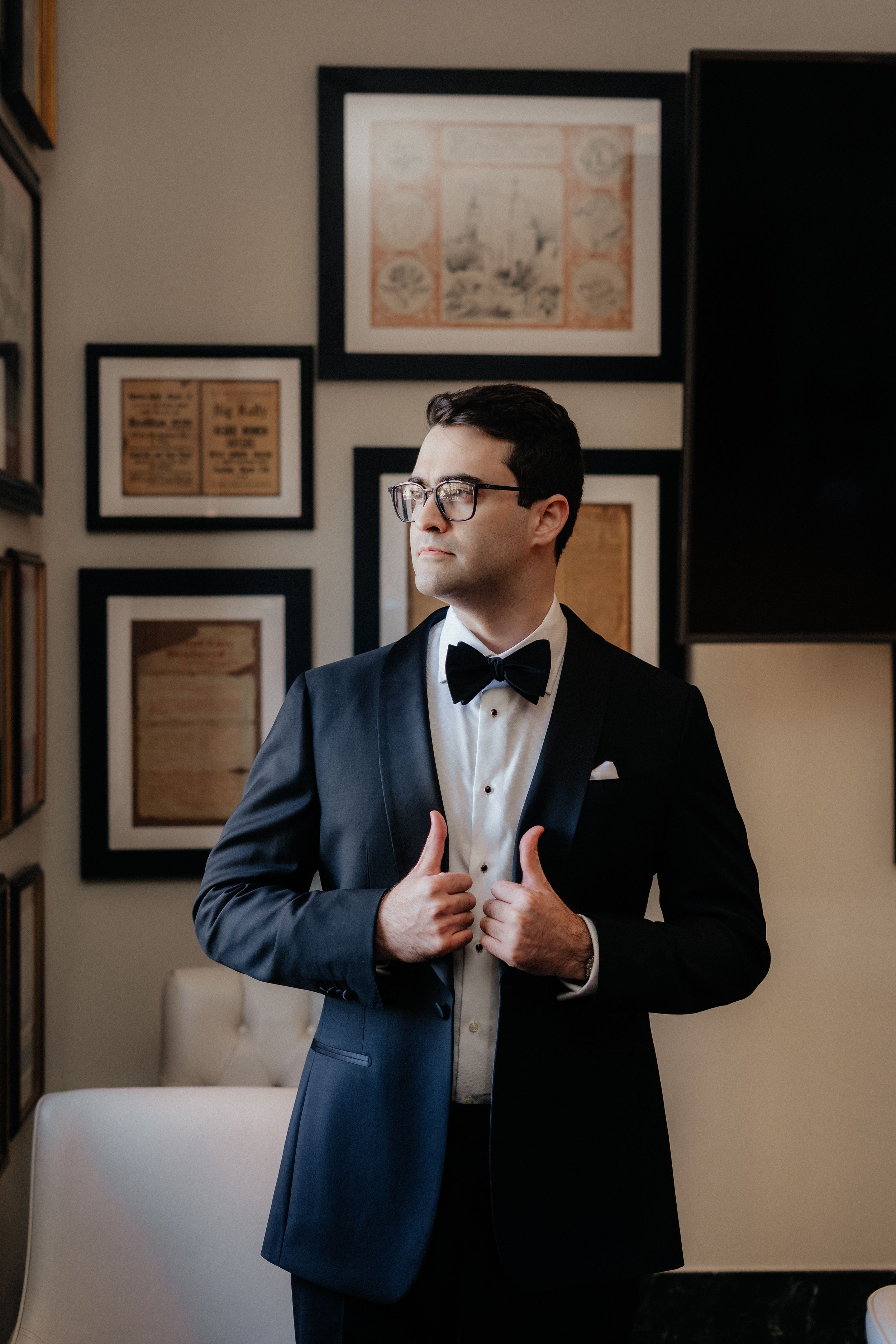 A series of photos showing a groom in a navy tuxedo and bow tie adjusting his jacket.