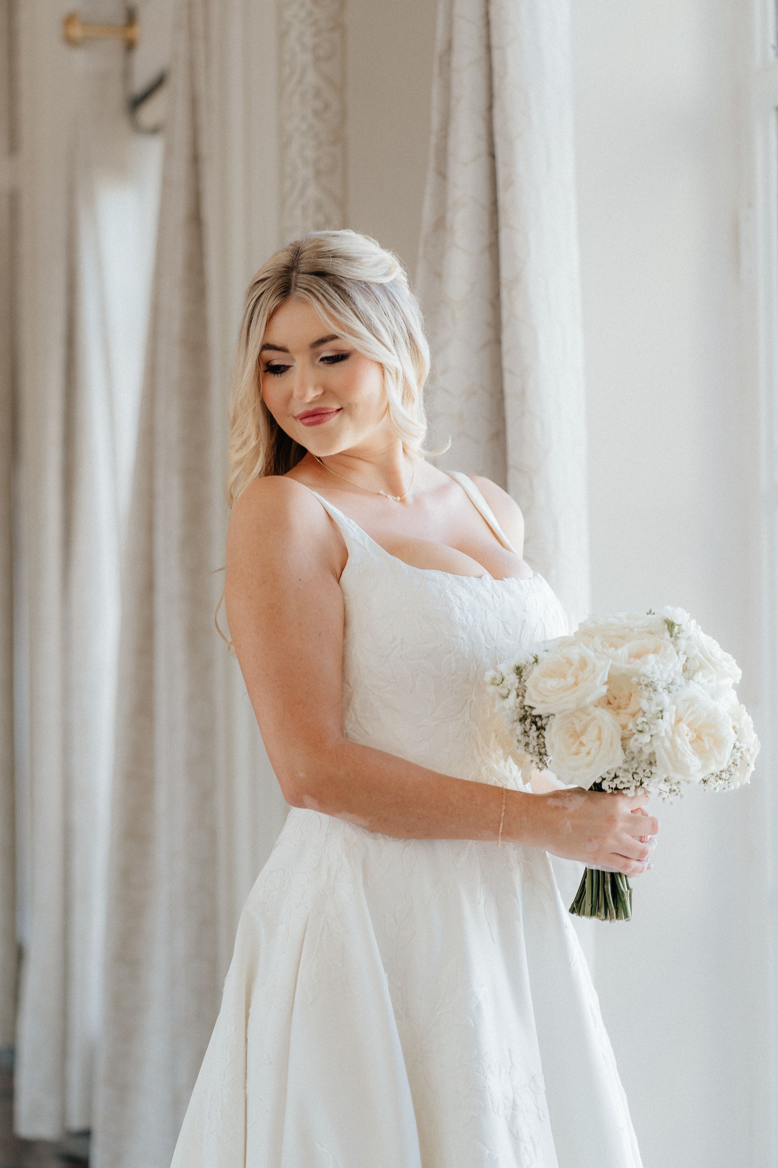 Elegant white wedding dress with sweetheart neckline and flowing fabric in a bright room.