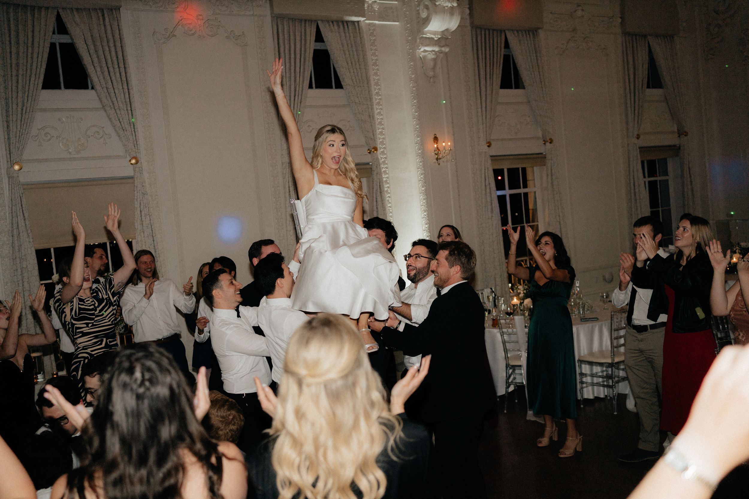 Wedding reception dance party with guests celebrating on a dimly lit dance floor.