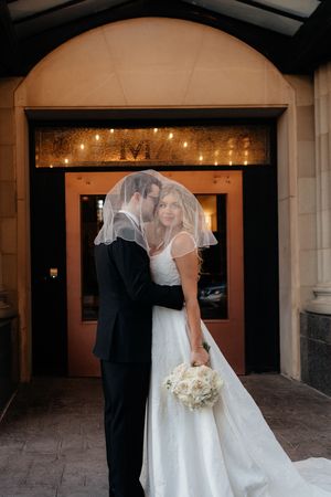 Romantic wedding couple sharing intimate moments in an archway with warm glowing lights in the background.