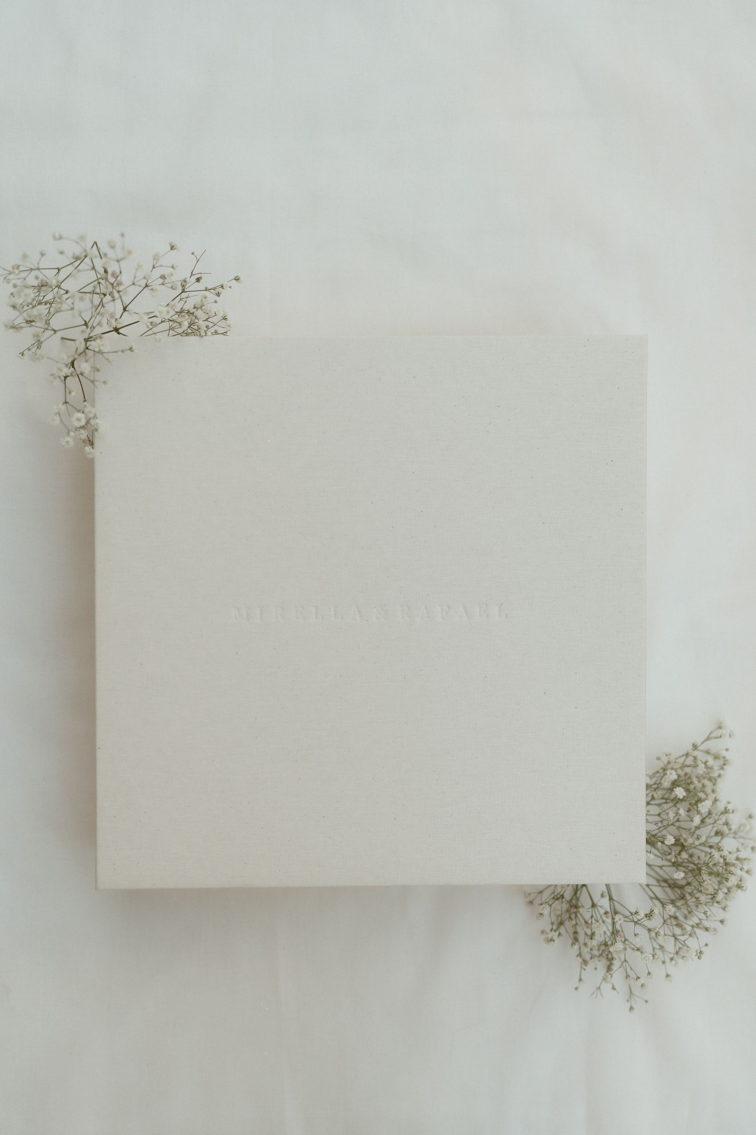 Minimalist white business cards arranged in a grid pattern with delicate dried baby's breath flowers on light background.