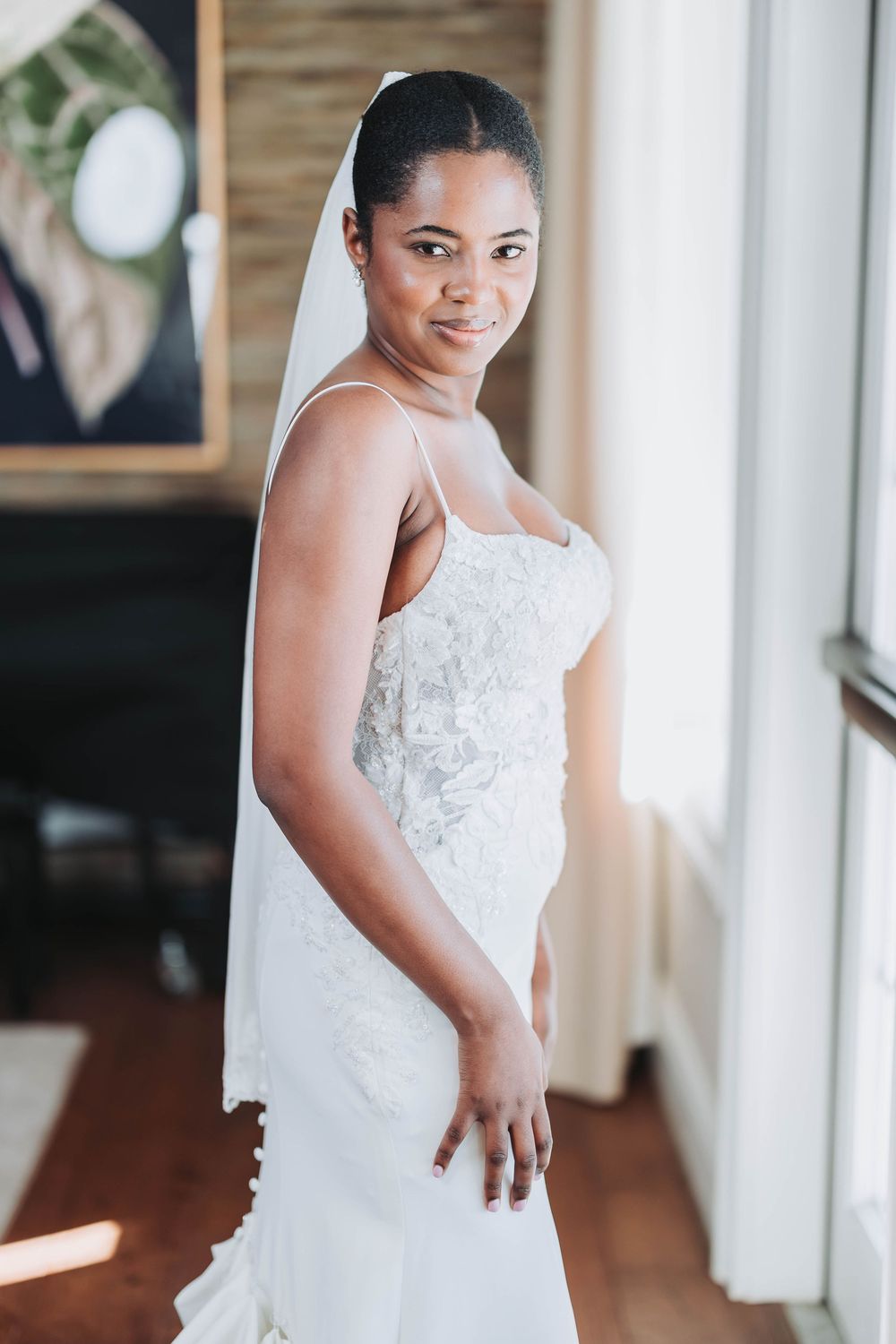 Elegant white wedding dress with delicate lace details and spaghetti straps photographed in natural light.