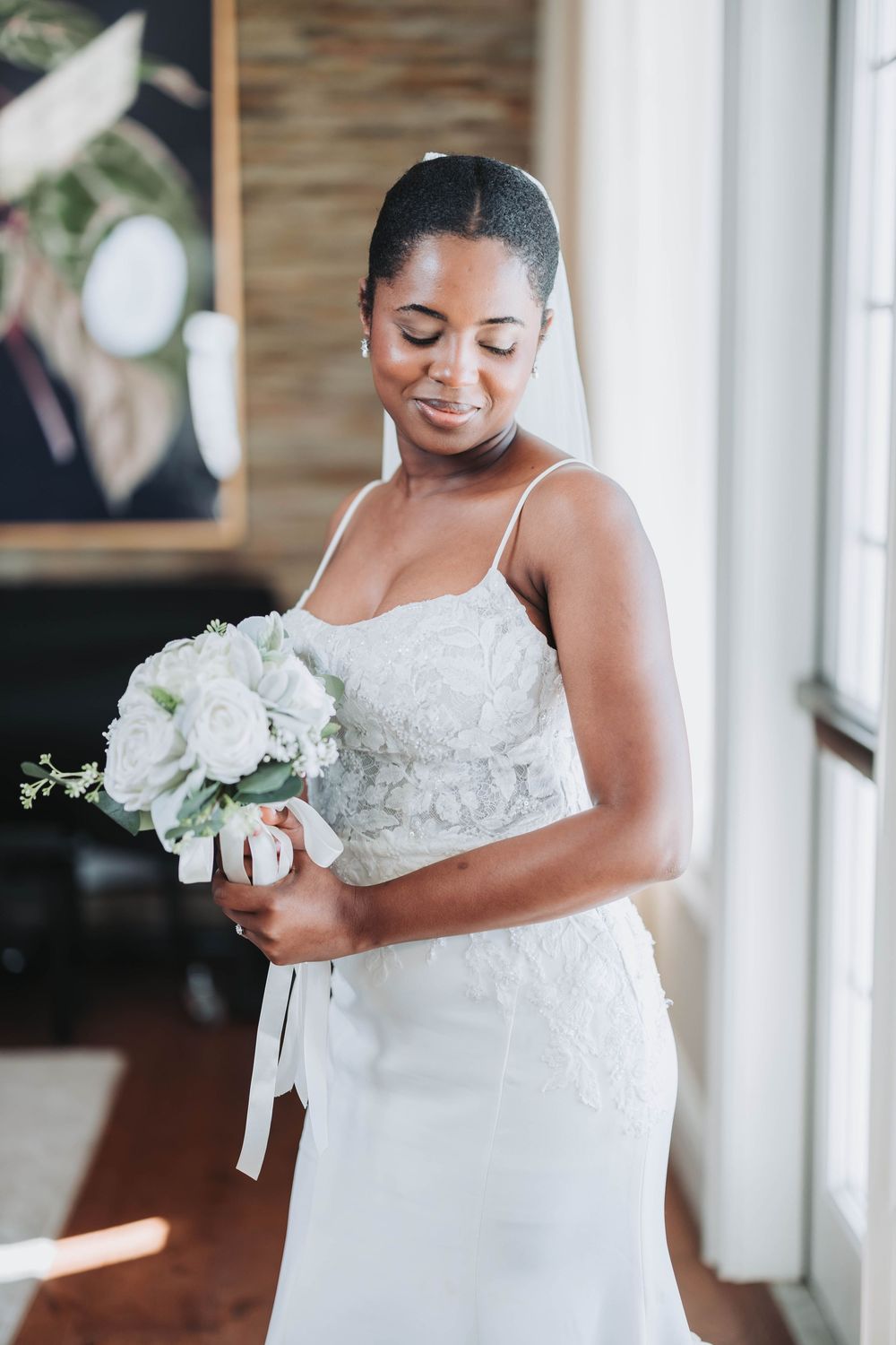 Bridal portrait showing a white wedding gown with lace details and a small white floral bouquet.
