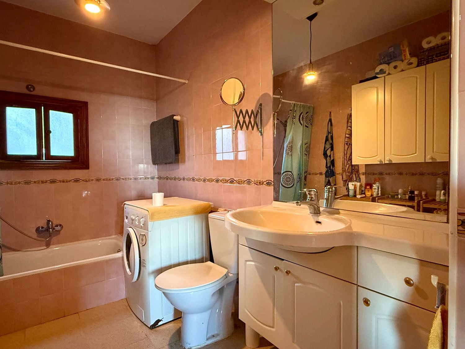 Panoramic view of a modern bathroom interior with white fixtures, pink walls, and pendant lighting.