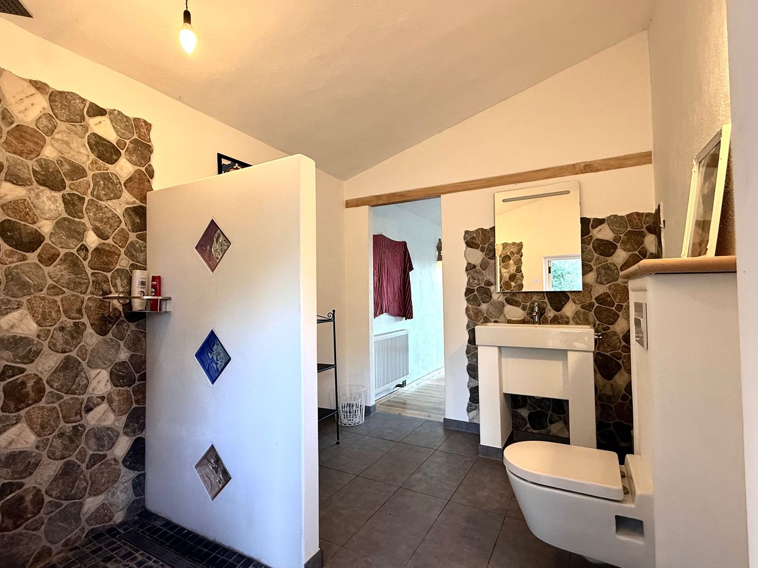Modern bathroom interior with stone accent wall, white walls, and diamond-shaped decorative elements.