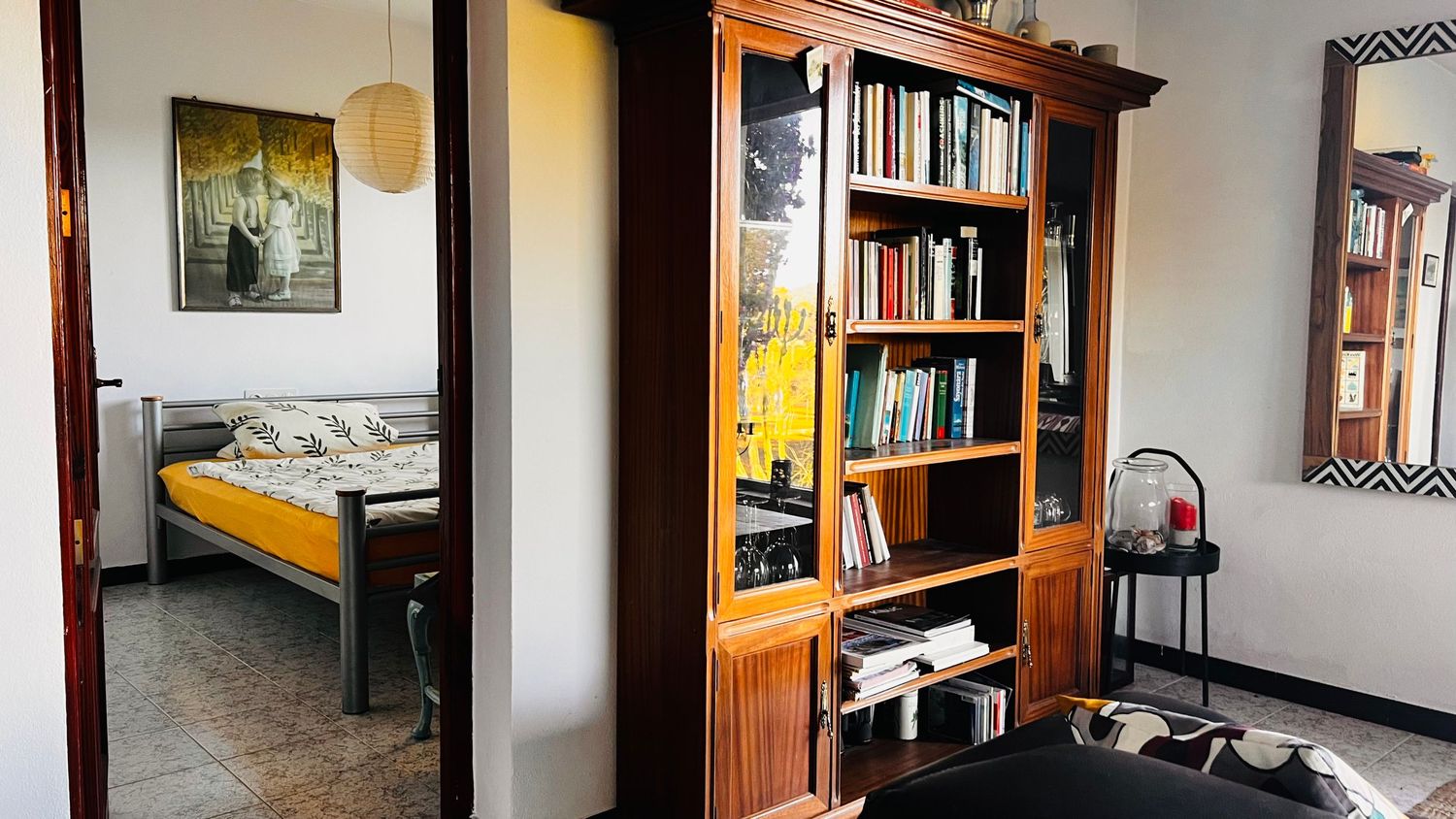Panoramic view of a cozy home library with wooden bookshelves, comfortable seating, and warm lighting.