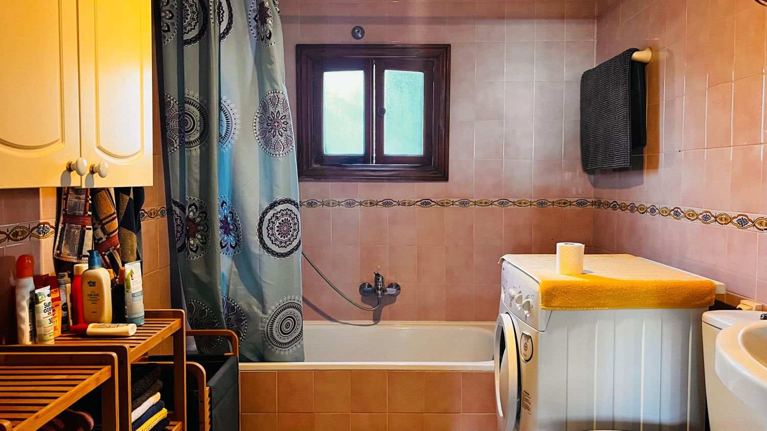 Panoramic shot of a peach-colored interior hallway with decorative wall sconces and hanging light fixtures.