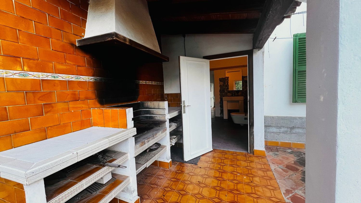 Long orange-tiled corridor with white pillars and fluorescent lighting in a modern building interior.