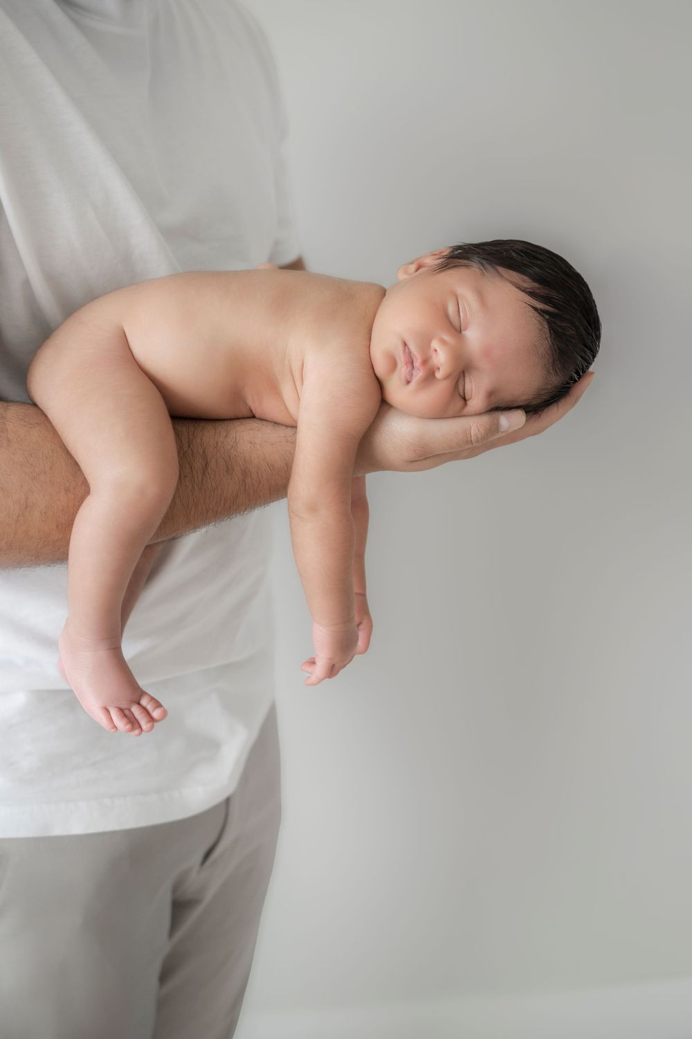 A sleeping baby lies peacefully on a white surface in a series of connected artistic photographs.