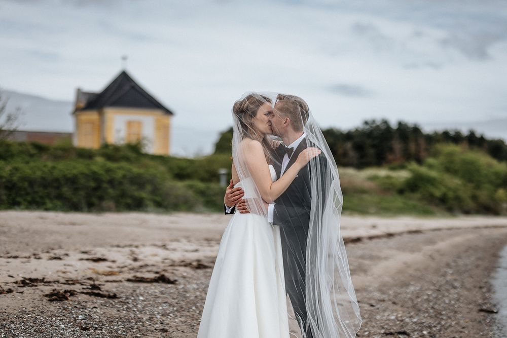 A series of romantic wedding photos showing couples embracing on a scenic beach with cloudy skies in the background.