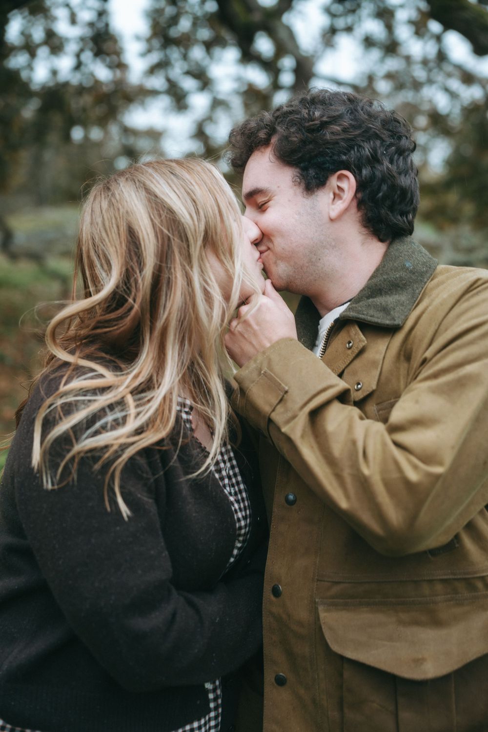 A romantic couple sharing a tender kiss outdoors on an autumn day while wearing cozy jackets.