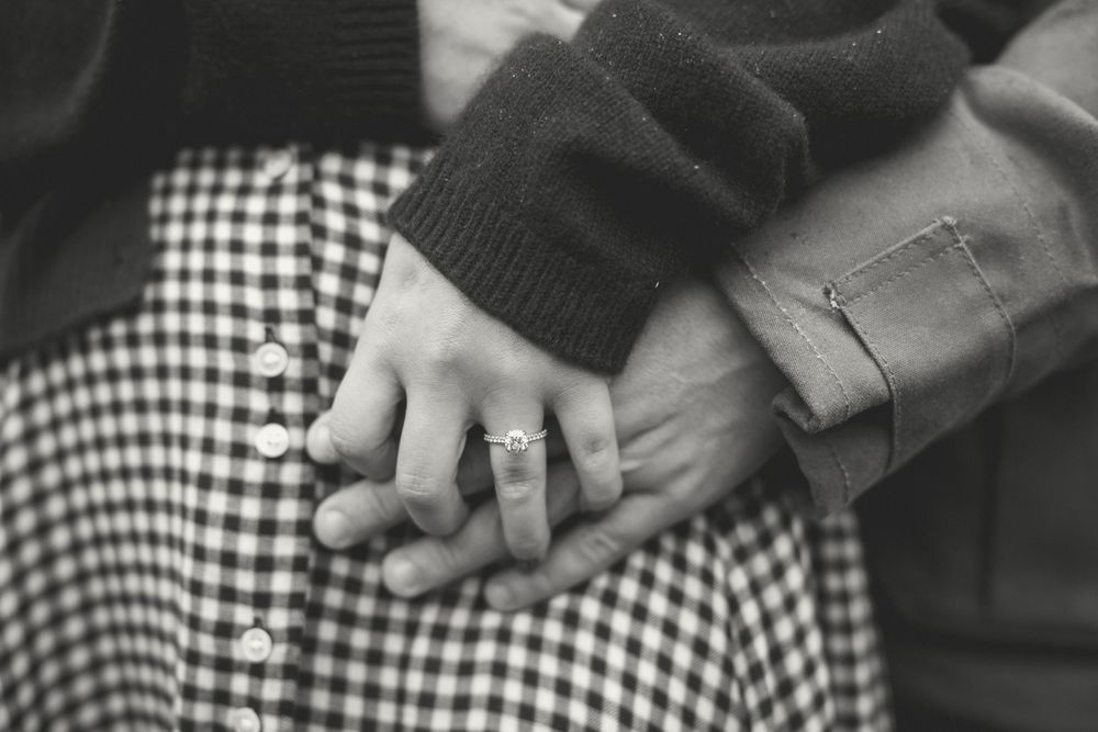 Close-up of intertwined hands showing affection and connection in black and white.