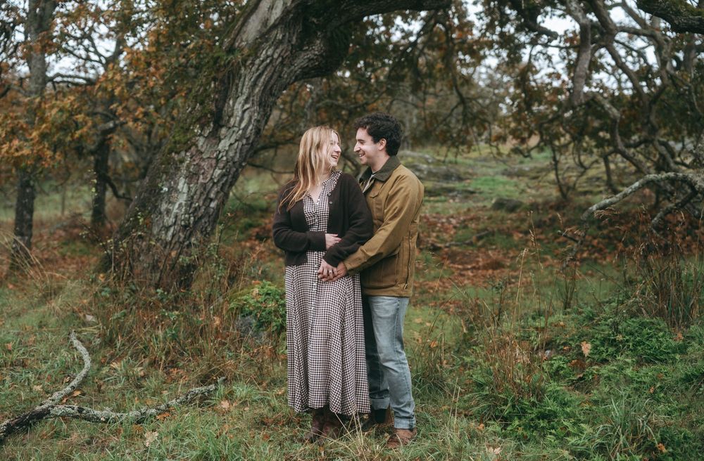 Couple sharing an intimate moment among autumn trees in a natural outdoor setting.