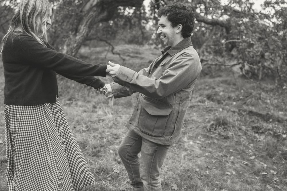 A couple shares a tender moment together outdoors during autumn wearing coordinated outfits.